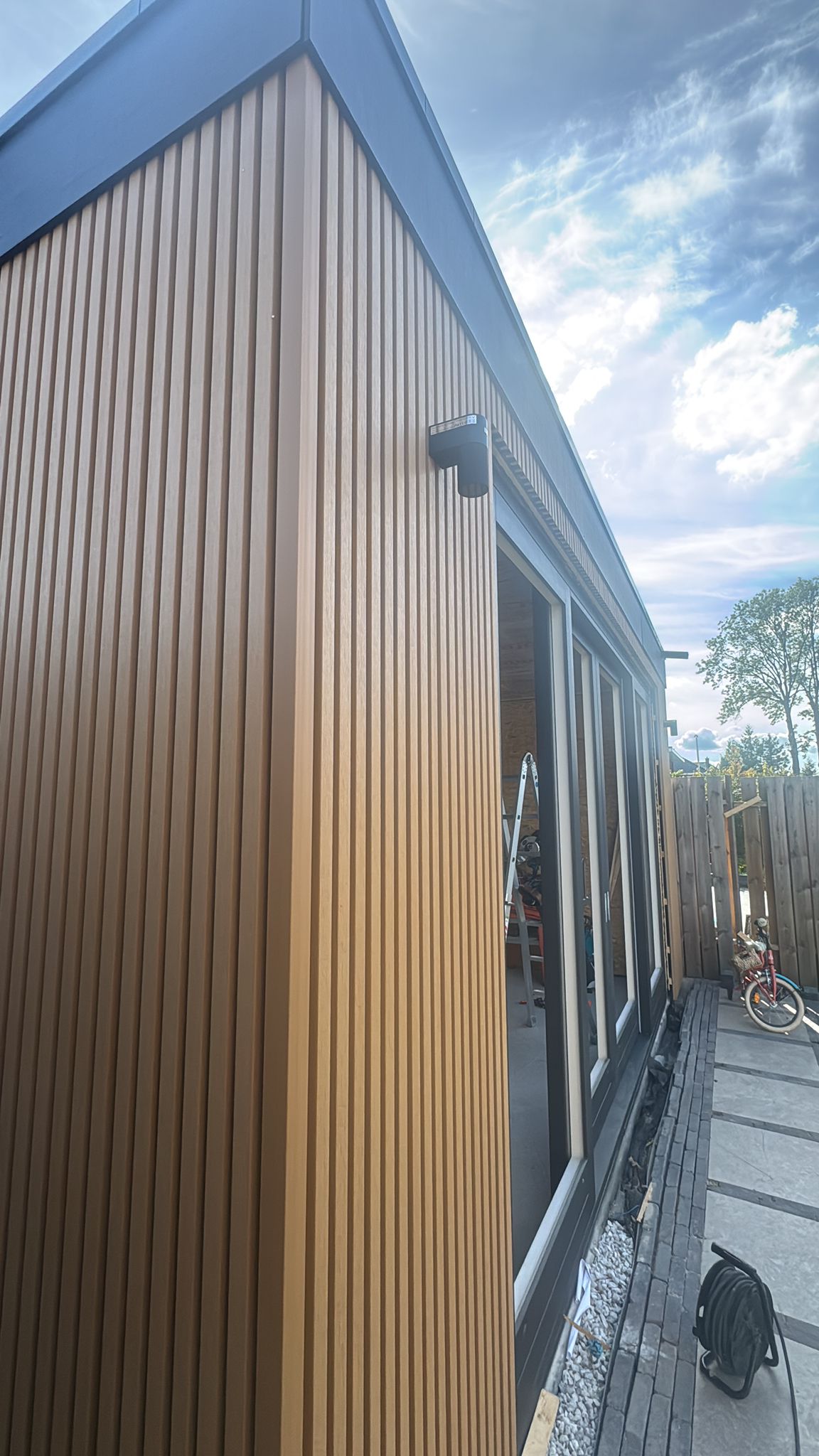 Hoekaanzicht aanbouw met houten gevelbekleding en schuifpui
