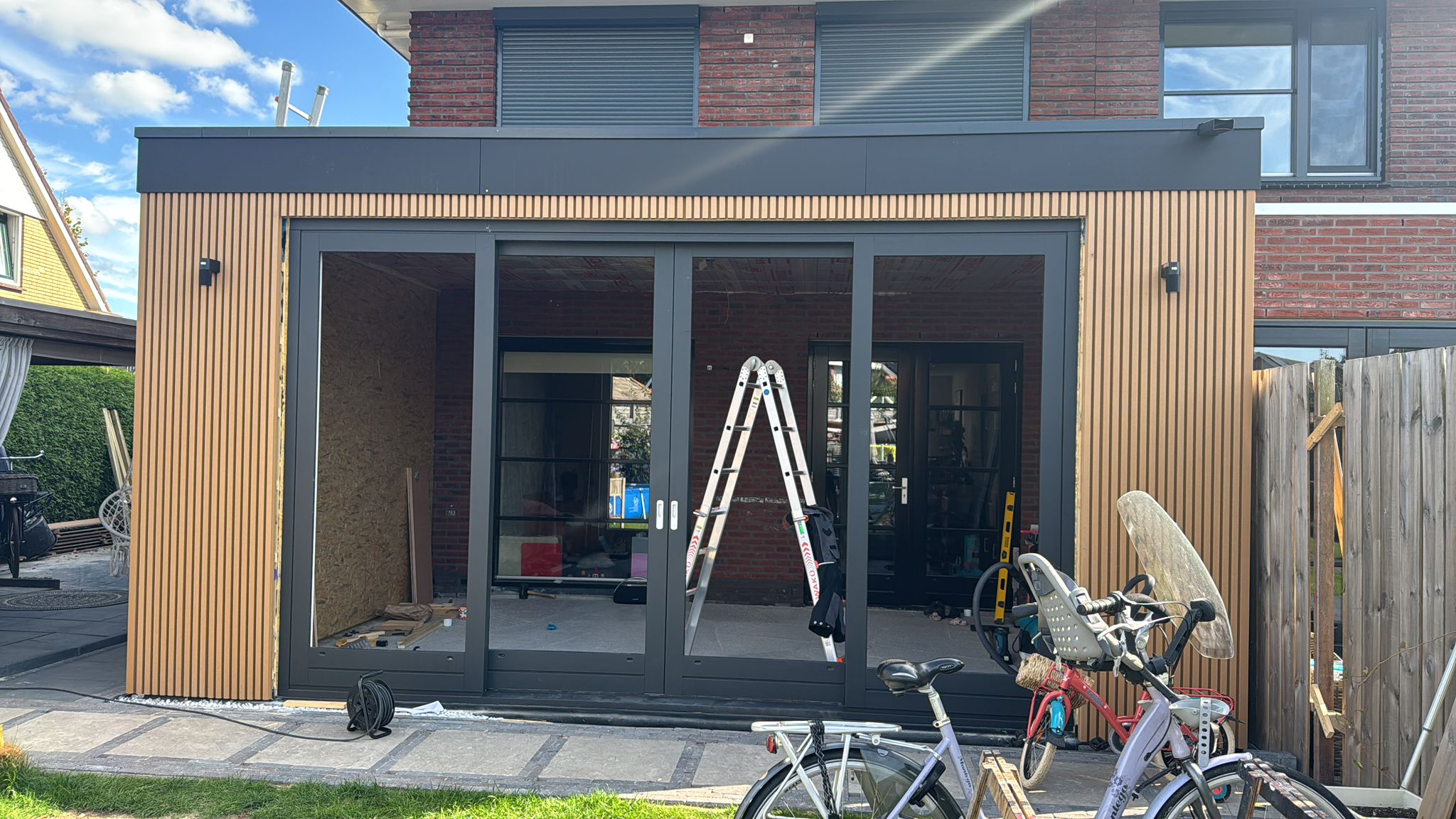 Vooraanzicht uitbouw met schuifpui en houten gevelbekleding door JM Totaalwerk